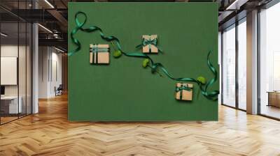 Composition with gift boxes, chrysanthemum flowers and green ribbon on color background Wall mural