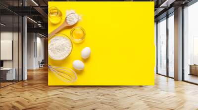 Composition with ingredients for baking and whisk on yellow background Wall mural