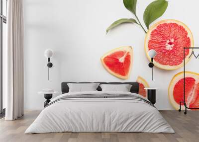 Composition with pieces of juicy grapefruit and plant leaves on white background Wall mural