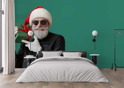 Cool Santa Claus in leather jacket holding gift on green background with space for text Wall mural