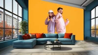 Cool young couple in hoodies on color background Wall mural