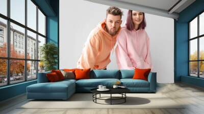 Cool young couple in hoodies on light background Wall mural