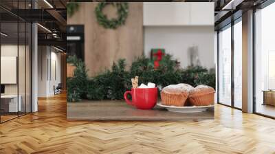 Cup of cocoa with muffins and Christmas branches on table in kitchen, closeup Wall mural