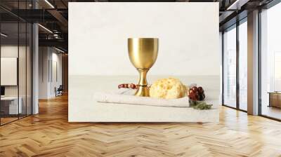 Cup of wine with bread and rosary on light background Wall mural