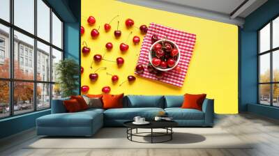 Cup with sweet cherries on yellow background Wall mural