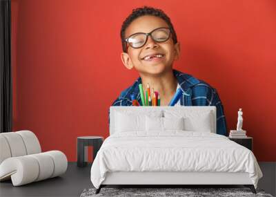 Cute African-American boy with pencils and markers on color background Wall mural