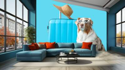 Cute Australian Shepherd dog in sunglasses with suitcase on blue background. Travel concept Wall mural