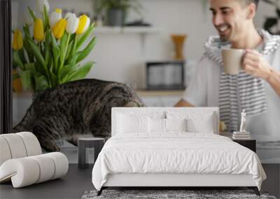 Cute cat eating food from bowl on dining table Wall mural