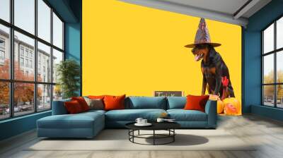 Cute Dobermann dog in witch hat with Halloween pumpkins and chalkboard sitting on yellow background Wall mural