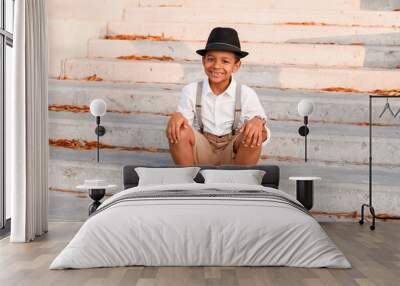 Cute fashionable African-American boy sitting on stairs outdoors Wall mural