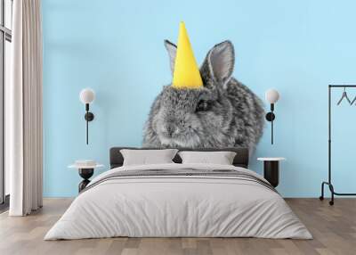 Cute fluffy rabbit in party hat on color background Wall mural