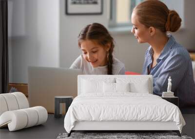 Cute girl with mother doing homework at home Wall mural