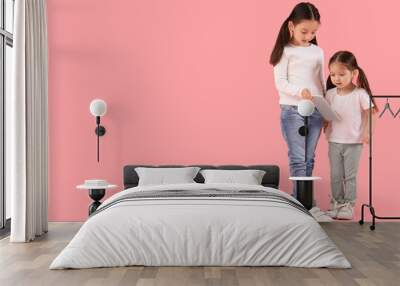 Cute little Asian happy sisters with tablet on pink background Wall mural