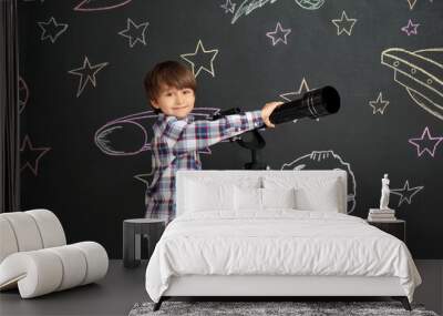 Cute little boy and telescope near black wall with drawn space Wall mural