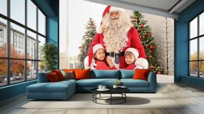 Cute little children hugging Santa Claus at home on Christmas eve Wall mural