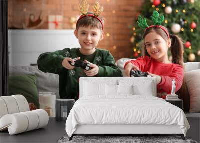 Cute little children playing video game at home on Christmas eve Wall mural