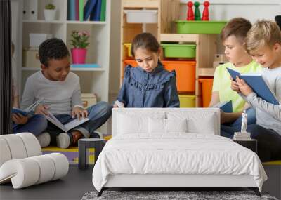 Cute little children reading books in playroom Wall mural