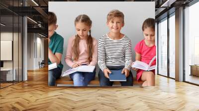 Cute little children reading books on grey background Wall mural