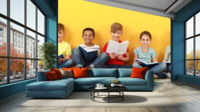 Cute little children reading books on yellow background Wall mural