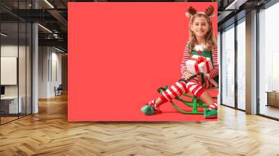 Cute little elves with Christmas gifts and sledge on red background with space for text Wall mural