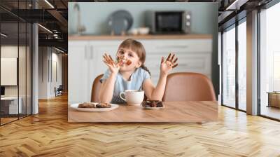 Cute little girl eating chocolate in kitchen Wall mural