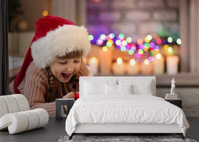 Cute little girl in Santa hat drinking hot chocolate and eating cookies at home on Christmas eve Wall mural