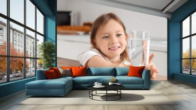 Cute little girl with glass of water on table in kitchen, closeup Wall mural