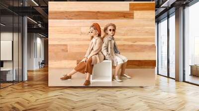 Cute little girls in autumn clothes near wooden wall Wall mural