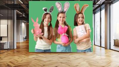 Cute little girls with Easter bunny ears, gifts and decor on green background Wall mural