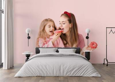 Cute mother and little daughter with tasty donuts on color background Wall mural