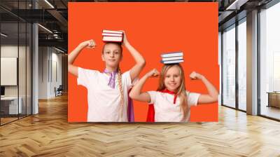 Cute teenage girls dressed as superhero with books on orange background. Library Lovers Day Wall mural