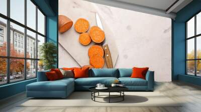 Cutting board and knife with raw sweet potato on light background Wall mural