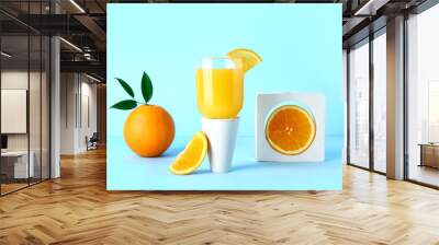 Decorative podium with glass of fresh orange juice on blue background Wall mural