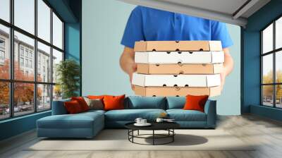 Delivery man with pizza boxes on color background Wall mural