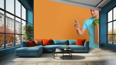 Delivery man with products and mobile phone on color background with space for text Wall mural