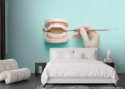 Dentist with tool and jaw model on color background Wall mural