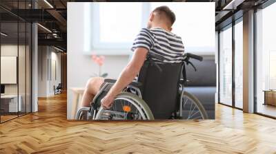 Depressed young man in wheelchair at home Wall mural