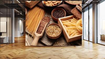 Different cereals, raw pasta and bread on wooden background, closeup Wall mural