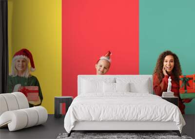 Different happy people with Christmas gifts on color background Wall mural