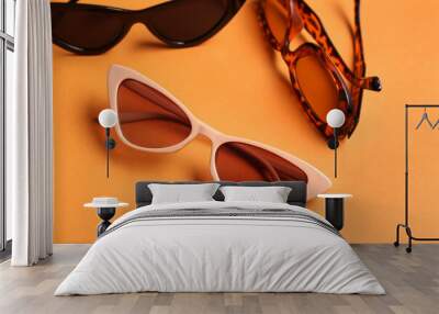 Different stylish eyeglasses on orange background Wall mural