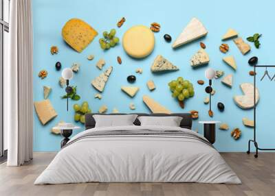 Different types of tasty cheese, nuts and grapes on blue background Wall mural