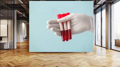 Doctor's hand holding test tubes with blood samples on color background Wall mural