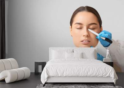 Doctor in protective gloves drawing marks on woman's nose for plastic surgery against white background Wall mural