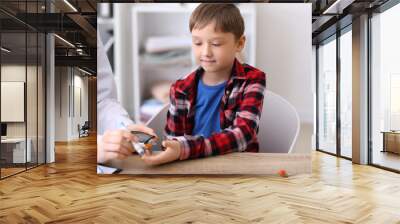 Doctor taking blood sample of diabetic child in clinic Wall mural