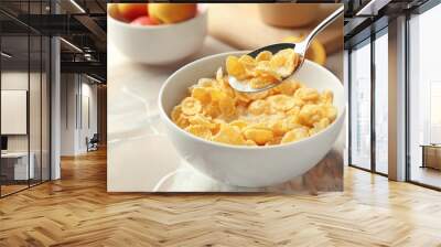 Eating of healthy cornflakes with milk from bowl on table, closeup Wall mural