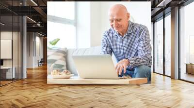 Elderly man with laptop at home Wall mural