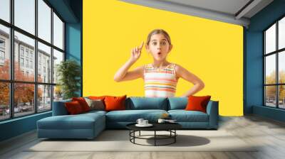 Emotional little girl with raised index finger on color background Wall mural