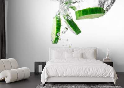 Falling of fresh cucumber slices into water against white background Wall mural