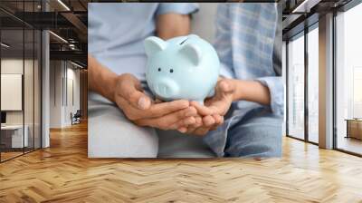 Family with piggy bank at home, closeup Wall mural