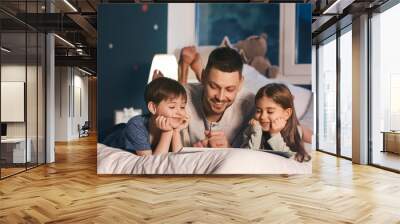 Father and his little children reading bedtime story at home Wall mural